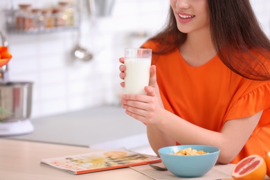Photo of Beautiful young woman drinking milk at table