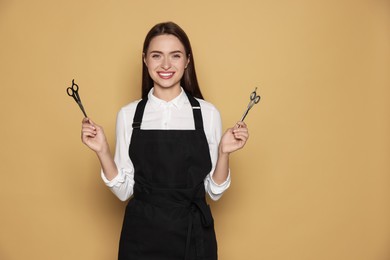 Photo of Portrait of happy hairdresser with professional scissors on beige background. Space for text