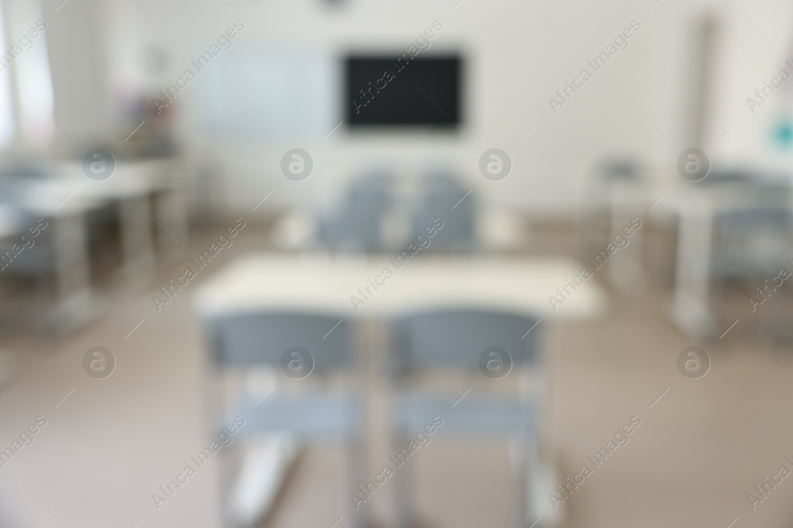 Photo of Blurred view of empty school classroom with desks and chairs