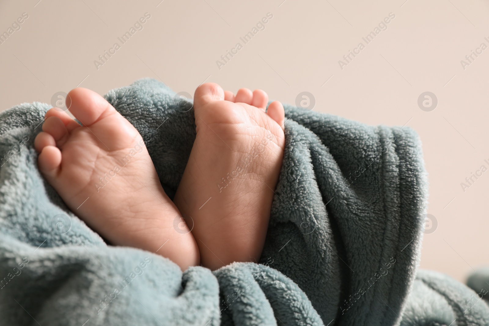 Photo of Little baby lying on soft blanket against light background, closeup. Space for text