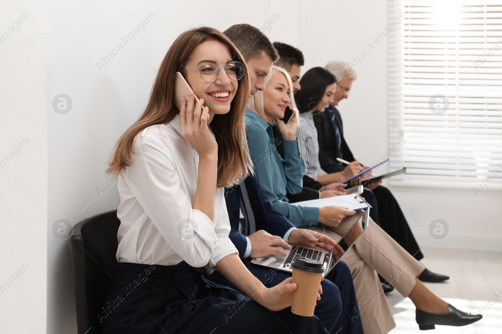 Photo of Woman with phone and cup of coffee waiting for interview in office