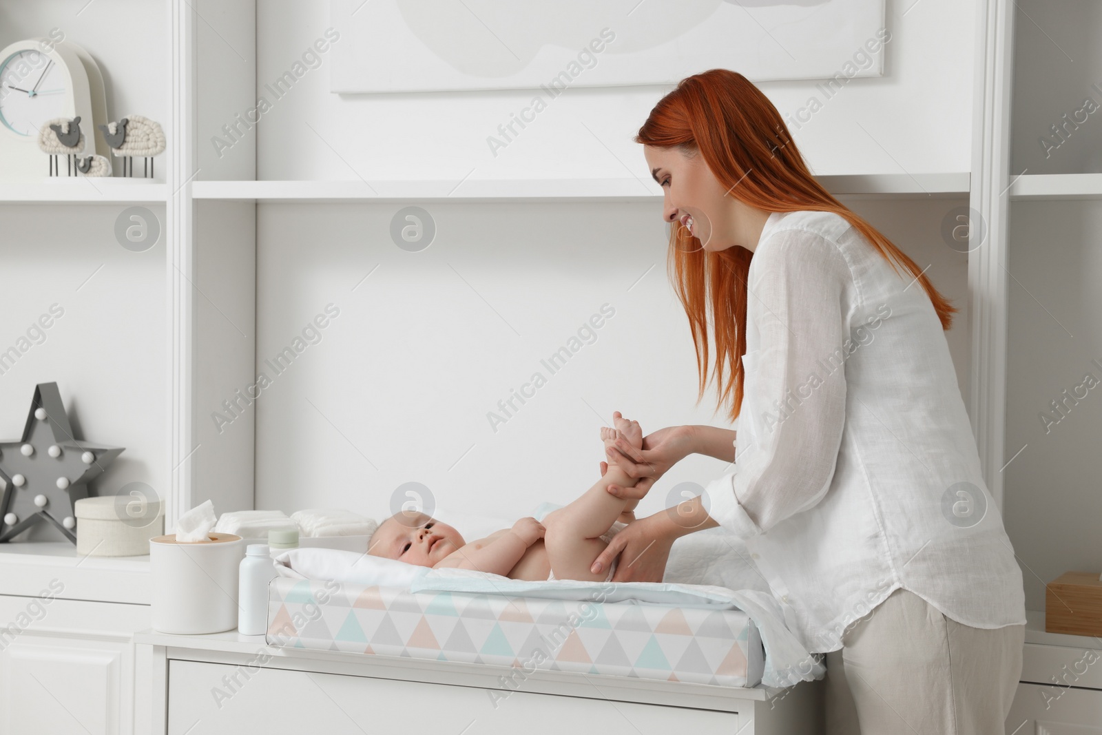 Photo of Mother changing her baby's diaper on table at home