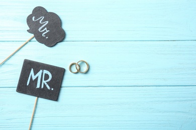 Flat lay composition with wedding rings and photo booth props on wooden background. Gay marriage