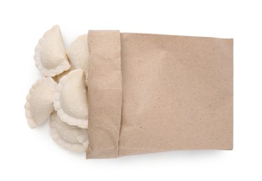 Photo of Paper bag of raw dumplings (varenyky) with tasty filling on white background, top view