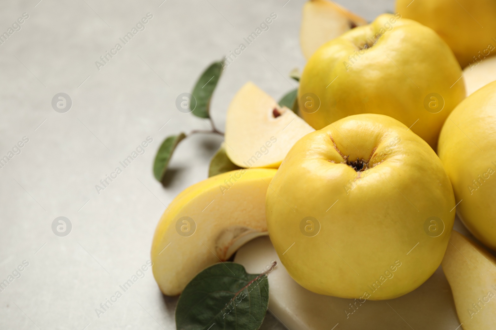 Photo of Fresh ripe organic quinces with leaves on grey table, closeup. Space for text