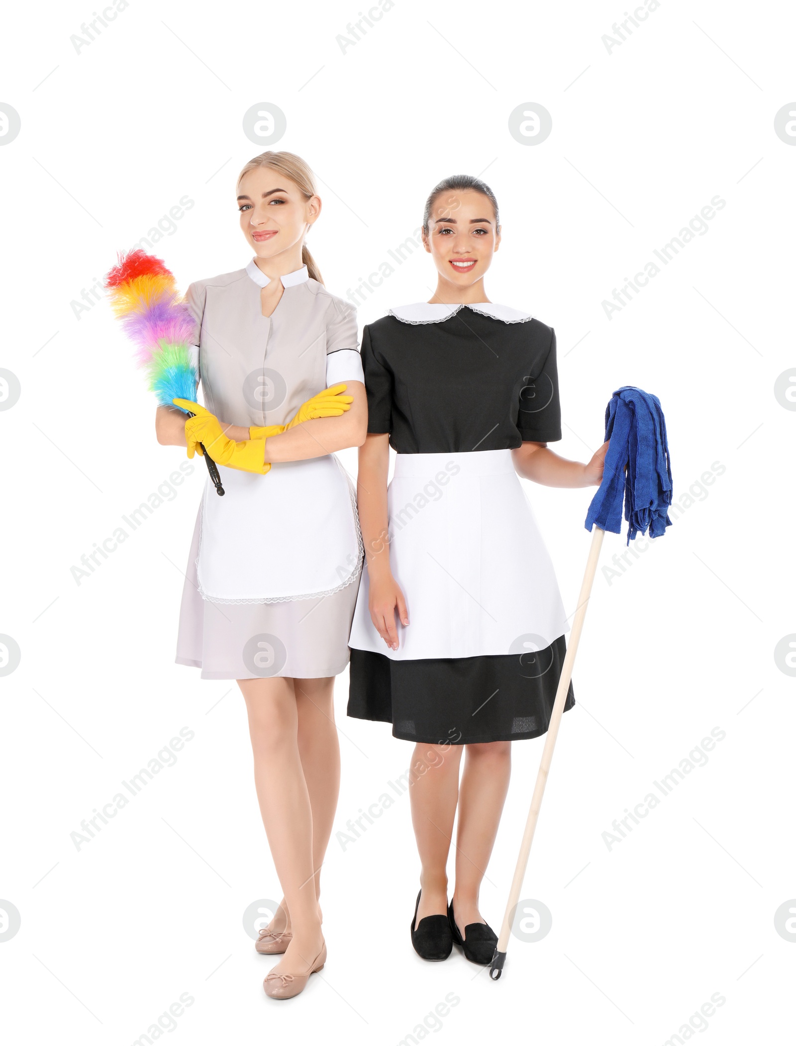 Photo of Young chambermaids with dusting brush and mop on white background