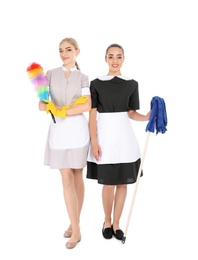 Young chambermaids with dusting brush and mop on white background