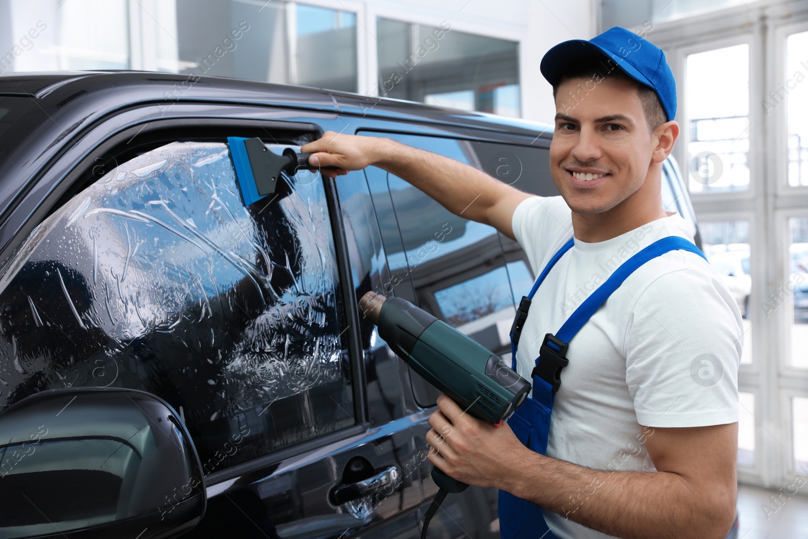 Photo of Worker tinting car window with foil in workshop