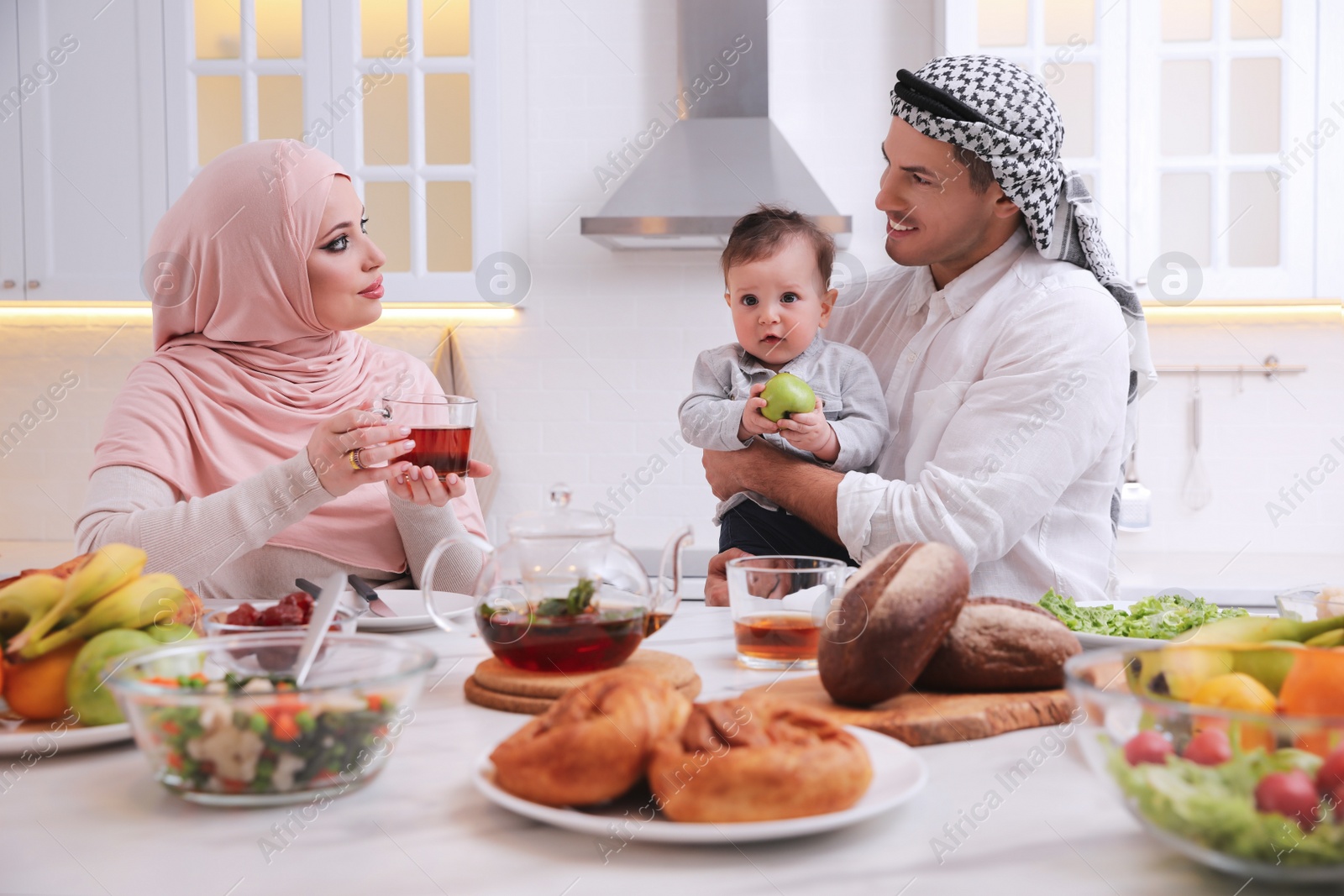 Photo of Happy Muslim family with little son at served table in kitchen