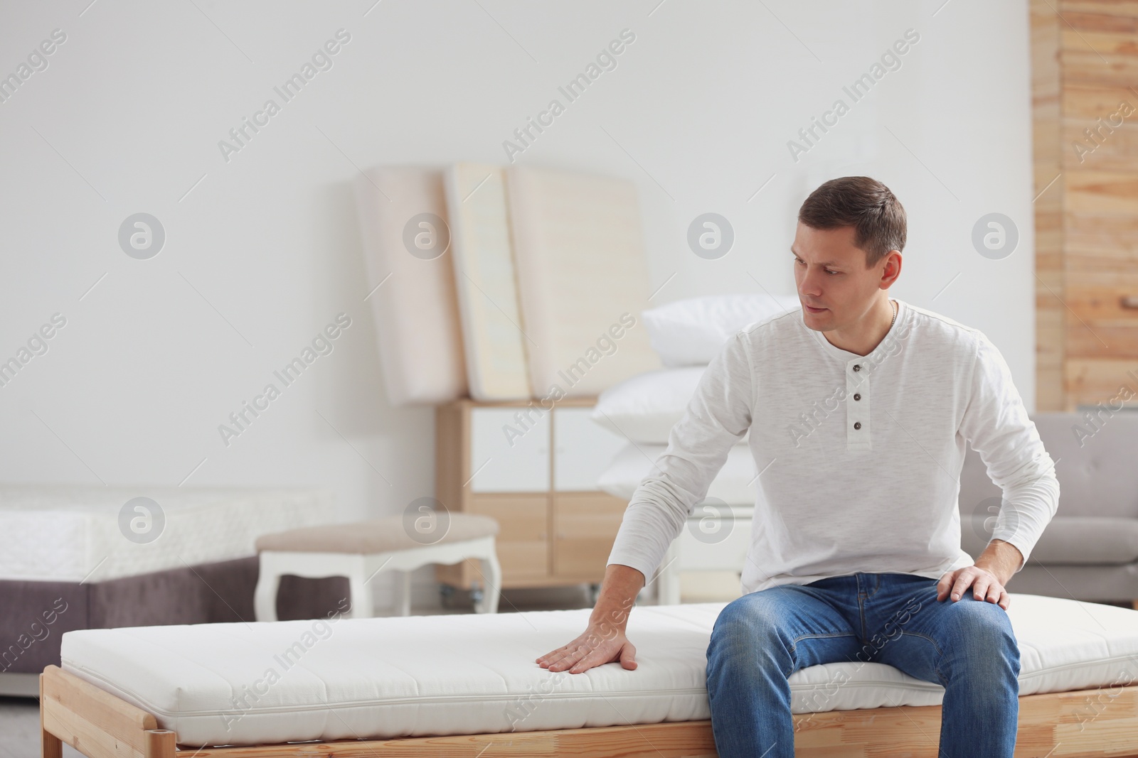 Photo of Man touching mattress in furniture store. Space for text