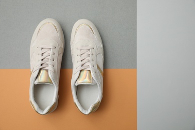 Image of Stylish white shoes on color background, top view