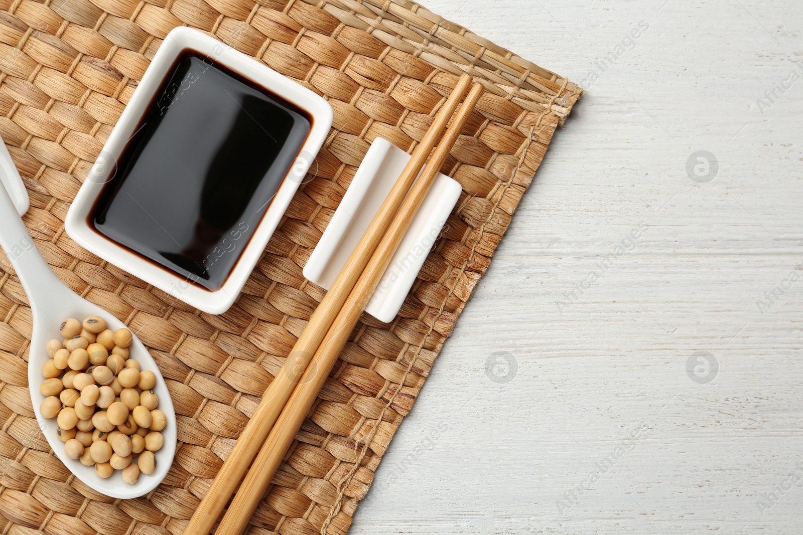 Photo of Dish of soy sauce served on wooden table, flat lay. Space for text