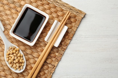 Dish of soy sauce served on wooden table, flat lay. Space for text