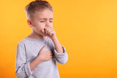 Photo of Sick boy coughing on yellow background, space for text. Cold symptoms