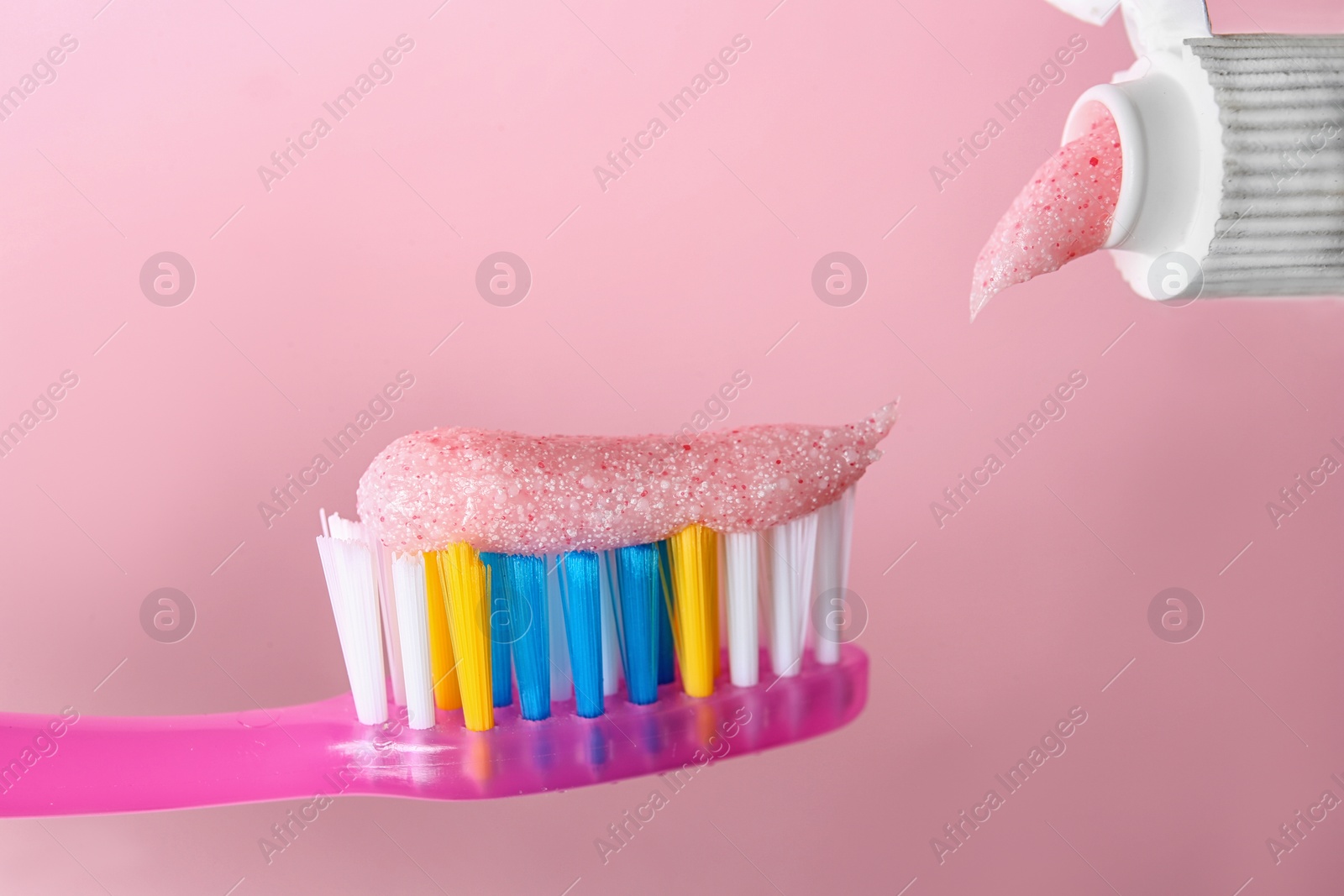 Photo of Applying paste on toothbrush against color background, closeup