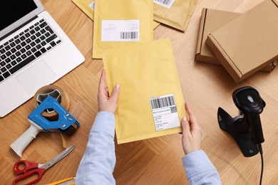 Photo of Post office worker packing parcel at wooden table, top view