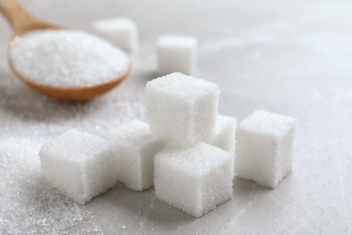 Heap of refined sugar cubes on light grey table, closeup