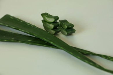 Green aloe vera leaves and slices on light background, closeup