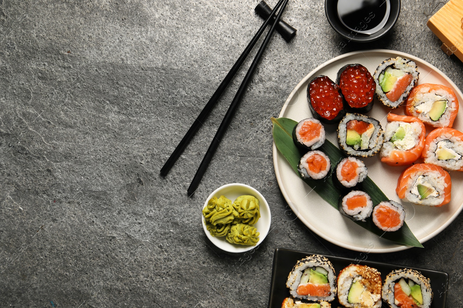 Photo of Flat lay composition with delicious sushi rolls on dark grey table. Space for text