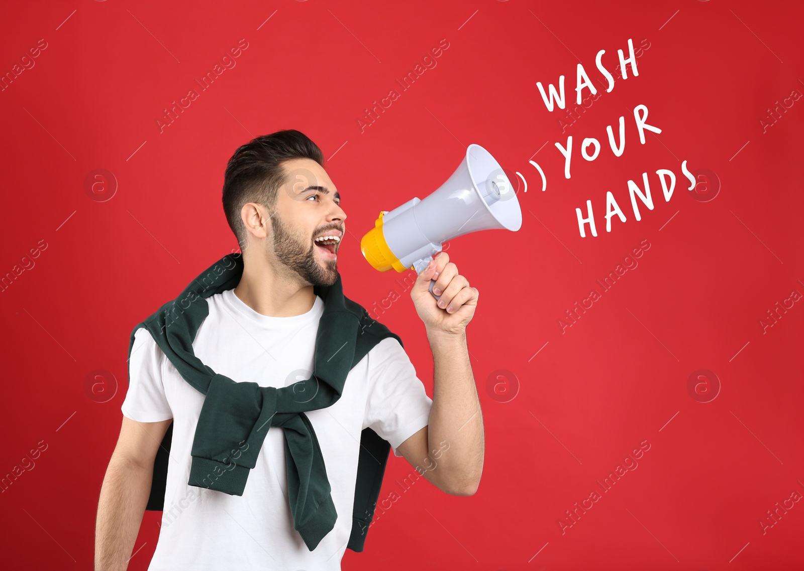Image of Young man with megaphone on red background. Wash your hands to avoid coronavirus