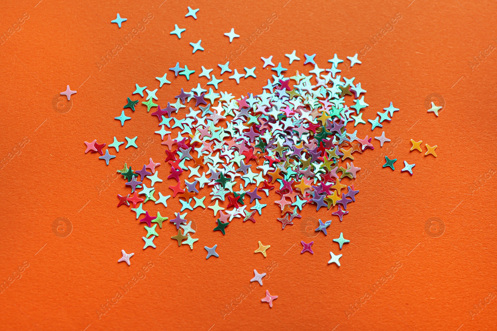 Photo of Shiny bright colorful glitter on orange background