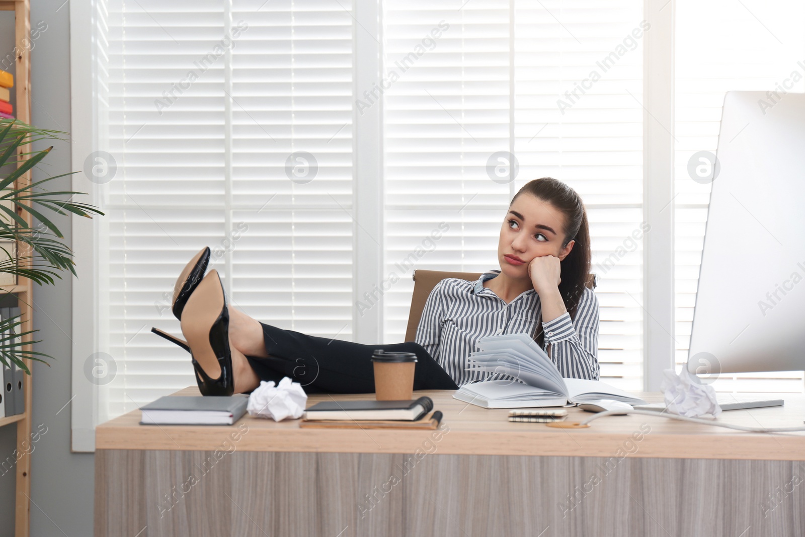 Photo of Lazy employee wasting time at table in office