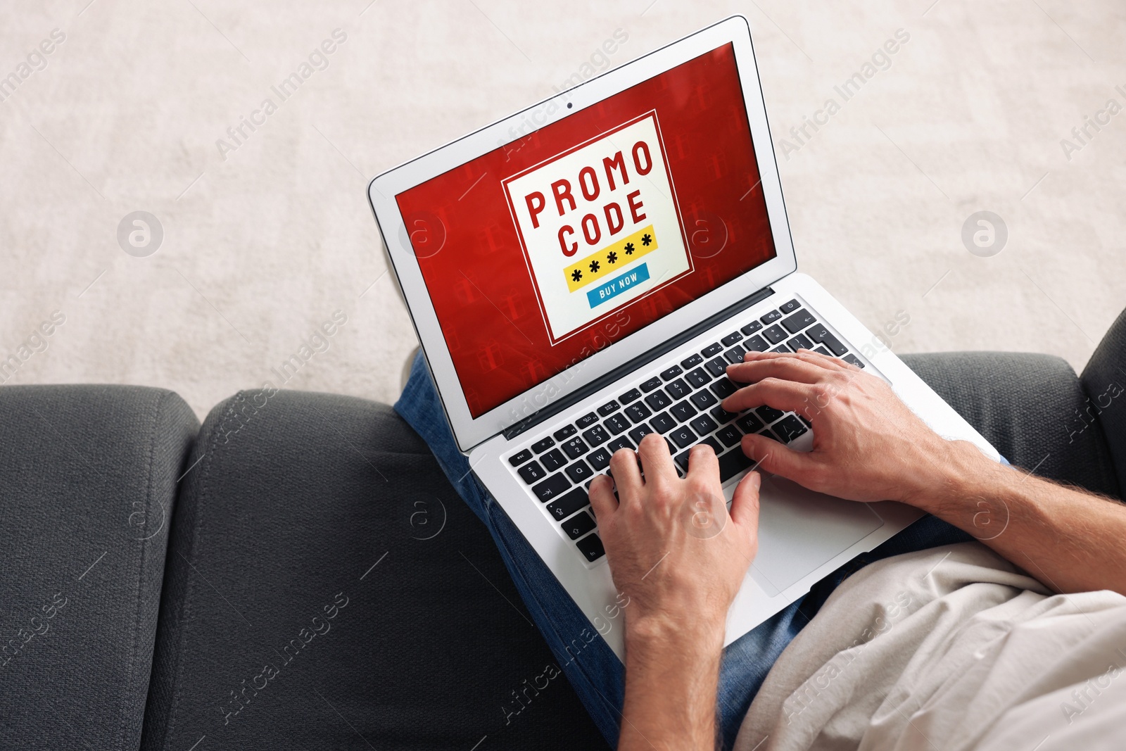 Photo of Man holding laptop with activated promo code on sofa, above view