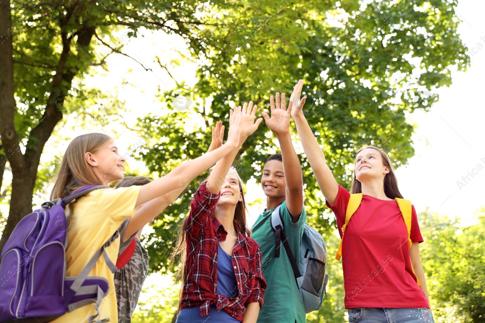 Photo of Group of children putting hands together outdoors. Summer camp