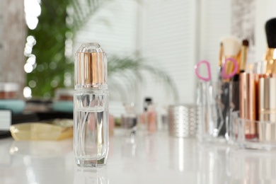 Photo of Bottle of luxury perfume and different makeup products on dressing table. Space for text