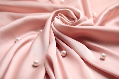 Photo of Many beautiful pearls on delicate pink silk, closeup