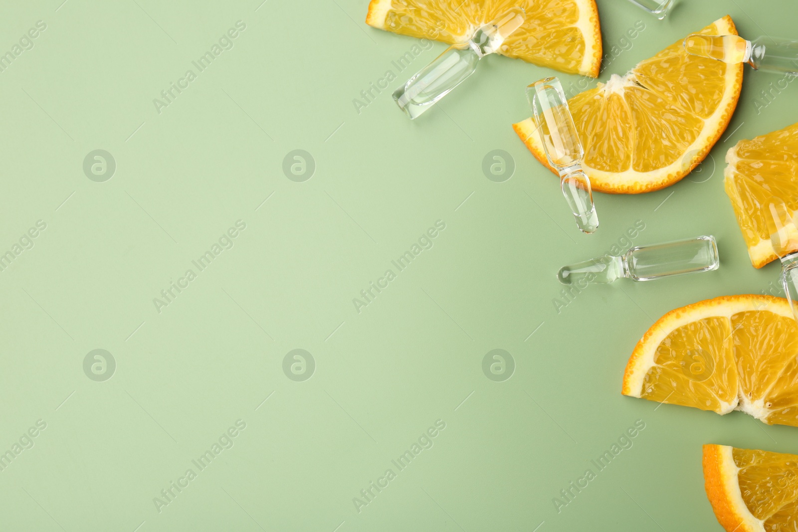 Photo of Skincare ampoules with vitamin C, slices of orange and leaves on light green background, flat lay. Space for text