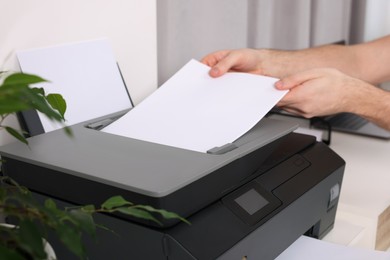 Photo of Man using modern printer at workplace indoors, closeup