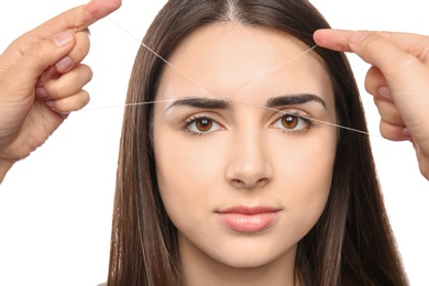 Young woman having eyebrow correction procedure on white background