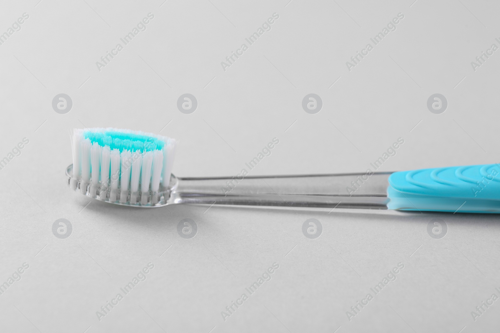 Photo of One plastic toothbrush on light background, closeup