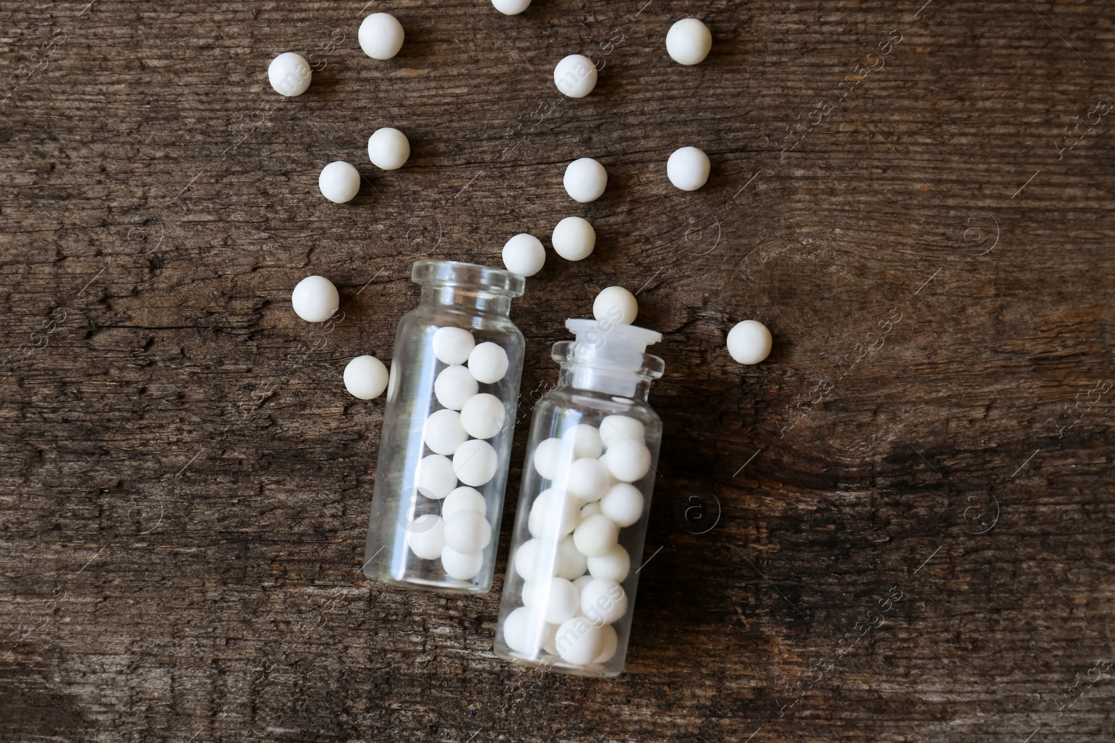 Photo of Bottles of homeopathic remedy on wooden background, flat lay