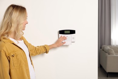 Photo of Woman entering code on home security system indoors