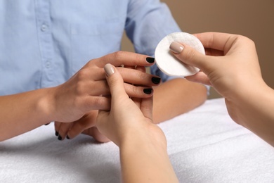 Photo of Manicurist removing polish from client's nails in salon, closeup