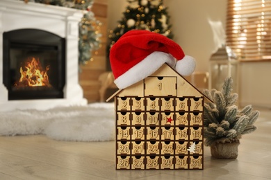 Wooden house shaped Advent calendar in room decorated for New Year