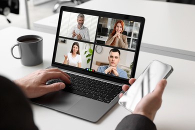 Image of Man having video chat with coworkers via laptop at white table, closeup