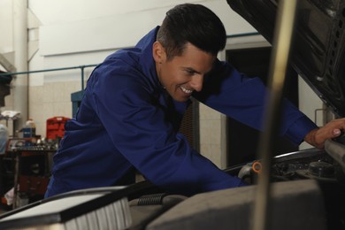 Professional mechanic fixing modern car at automobile repair shop