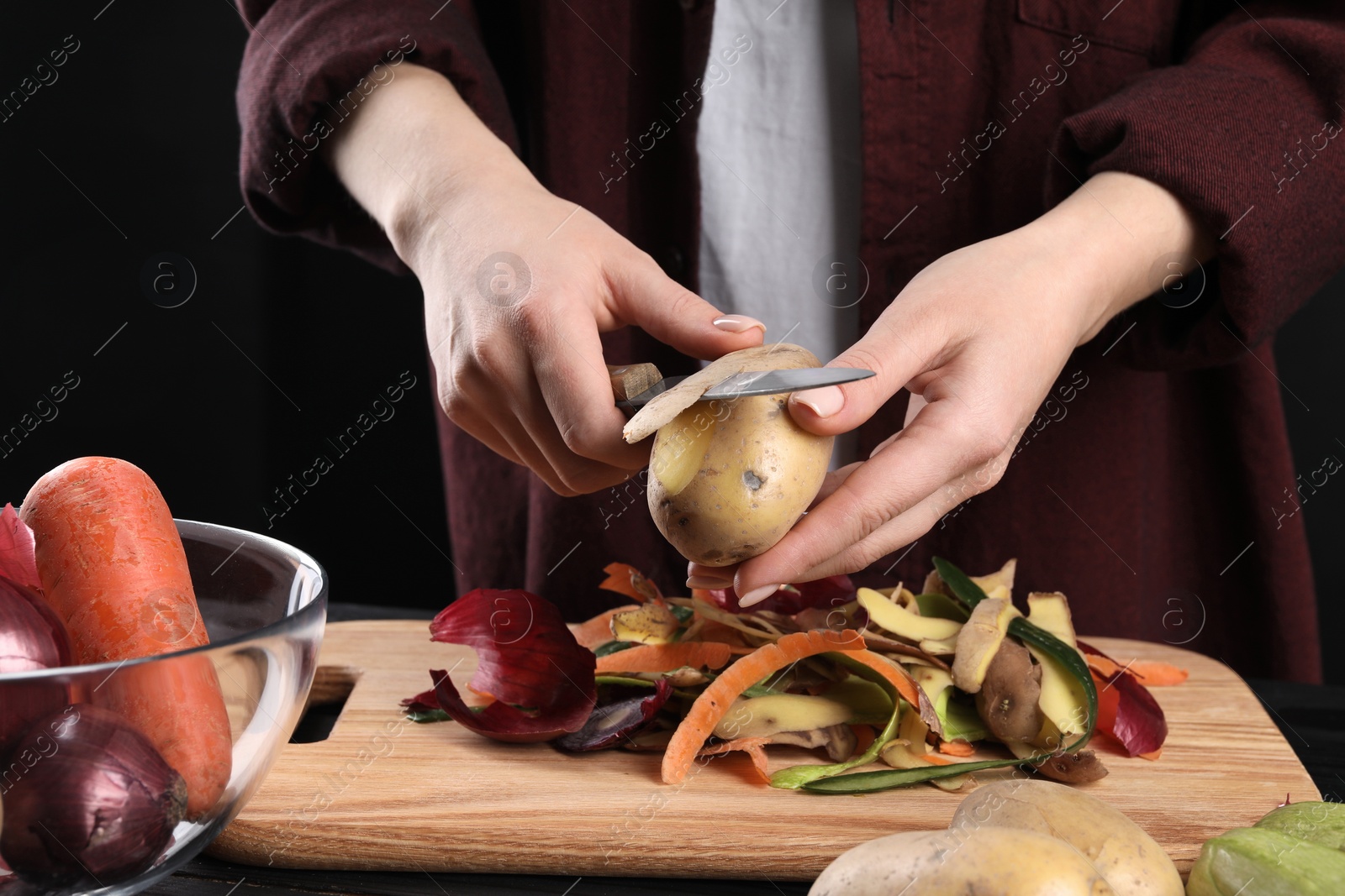 Photo of Woman peeling fresh potato with knife at table, closeup