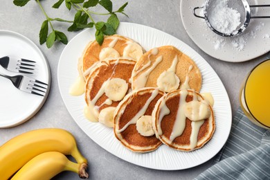 Photo of Tasty pancakes with sliced banana served on grey table, flat lay
