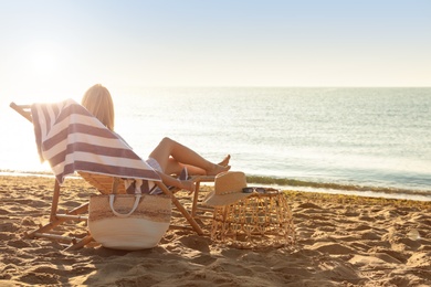 Woman relaxing on deck chair at sandy beach. Summer vacation