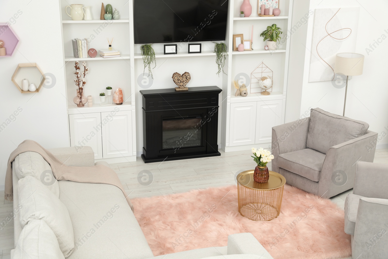 Photo of Stylish room interior with beautiful fireplace, armchairs, sofa and shelves with decor