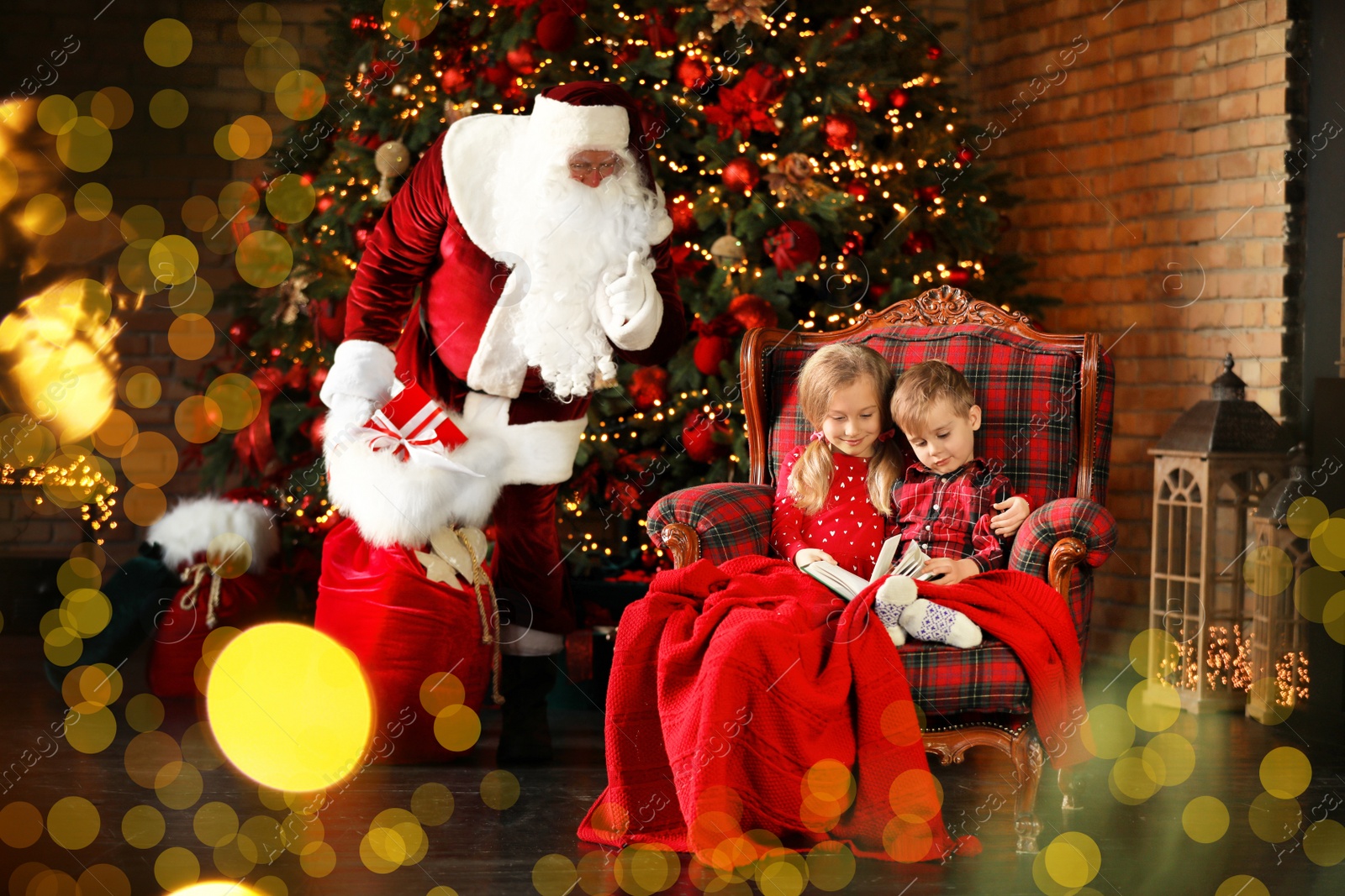 Photo of Santa Claus sneaking in with gifts while children reading book near Christmas tree indoors