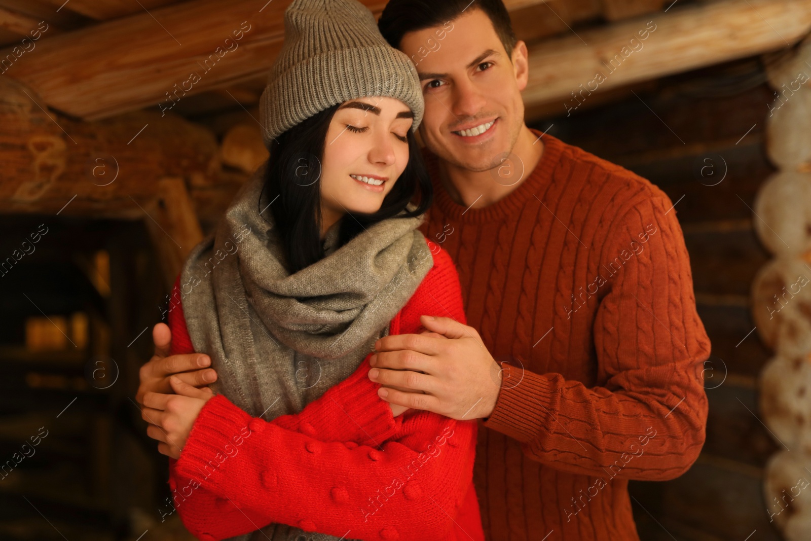 Photo of Lovely couple wearing warm sweaters indoors. Winter season