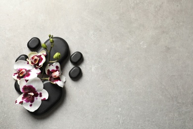 Flat lay composition with spa stones and orchid flowers on grey background. Space for text