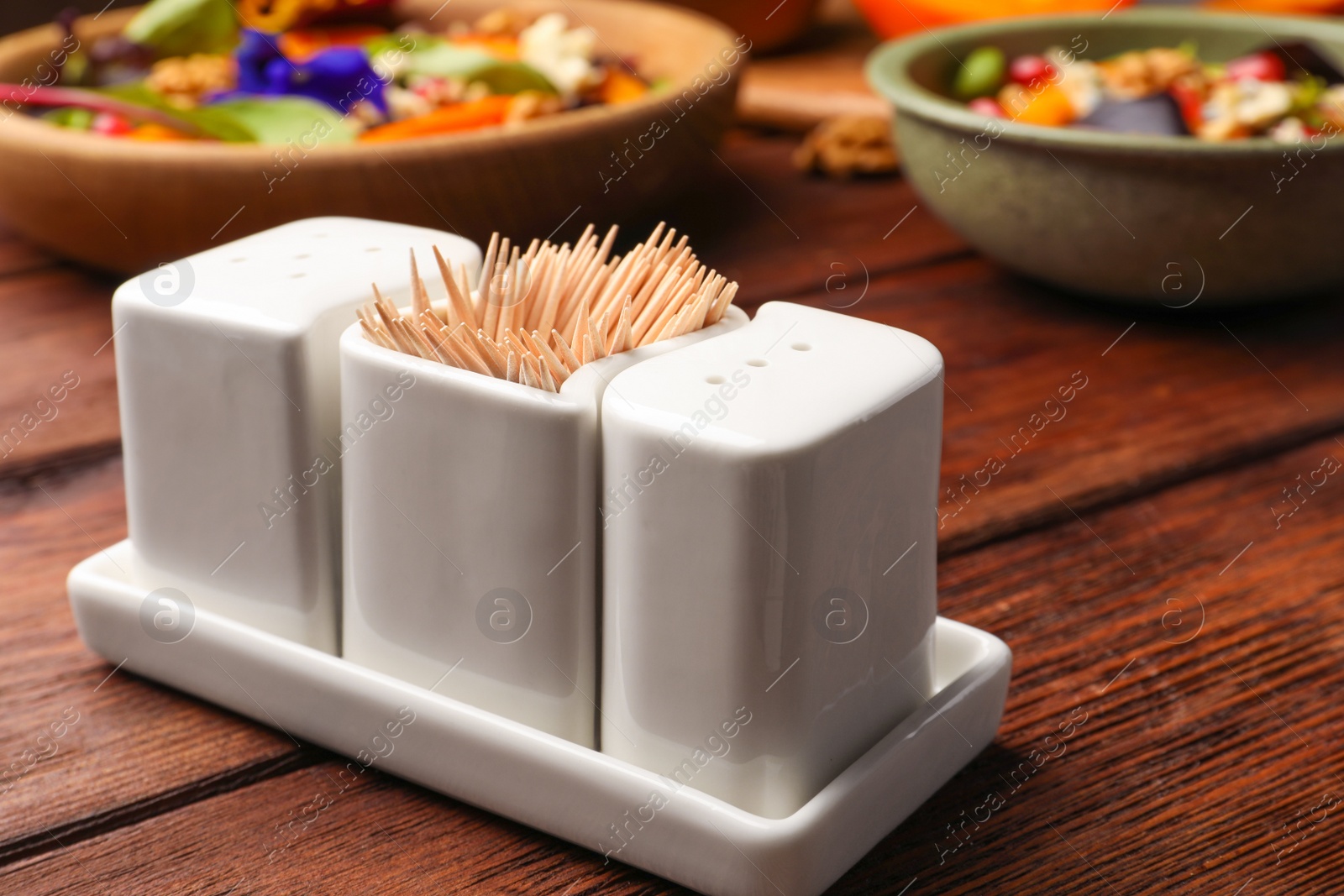 Photo of Holder with salt, pepper and toothpicks on wooden table, closeup