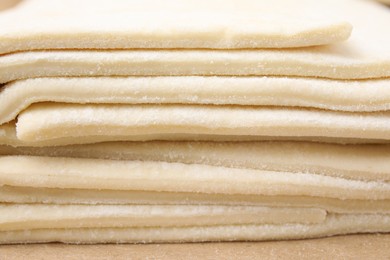 Photo of Stacked sheets of raw puff pastry dough as background, closeup