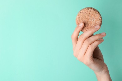 Photo of Woman holding solid shampoo bar against turquoise background, closeup. Space for text